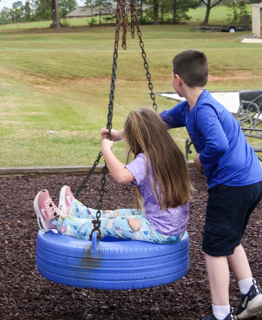 brother pushing sister on tire swing